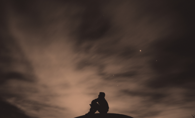 a man thinking under a sky full of stars